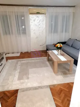 Living room with a sectional sofa, coffee table, and air conditioning unit. - image 10