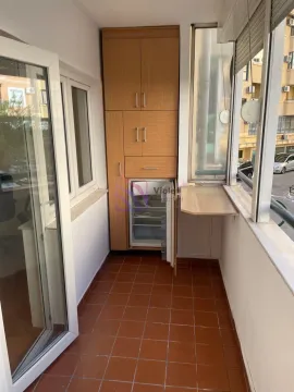 Enclosed balcony with a built-in wooden cabinet and a small refrigerator. - image 4