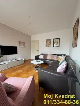 Living room with a sofa set, television, and wooden flooring. - image 2