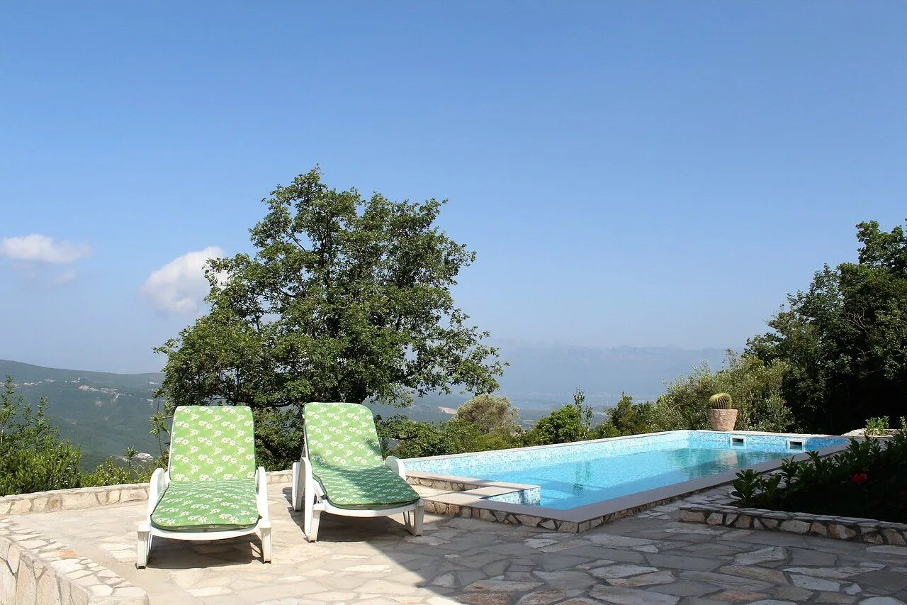Swimming pool with loungers and a view of nature and mountains in the background.