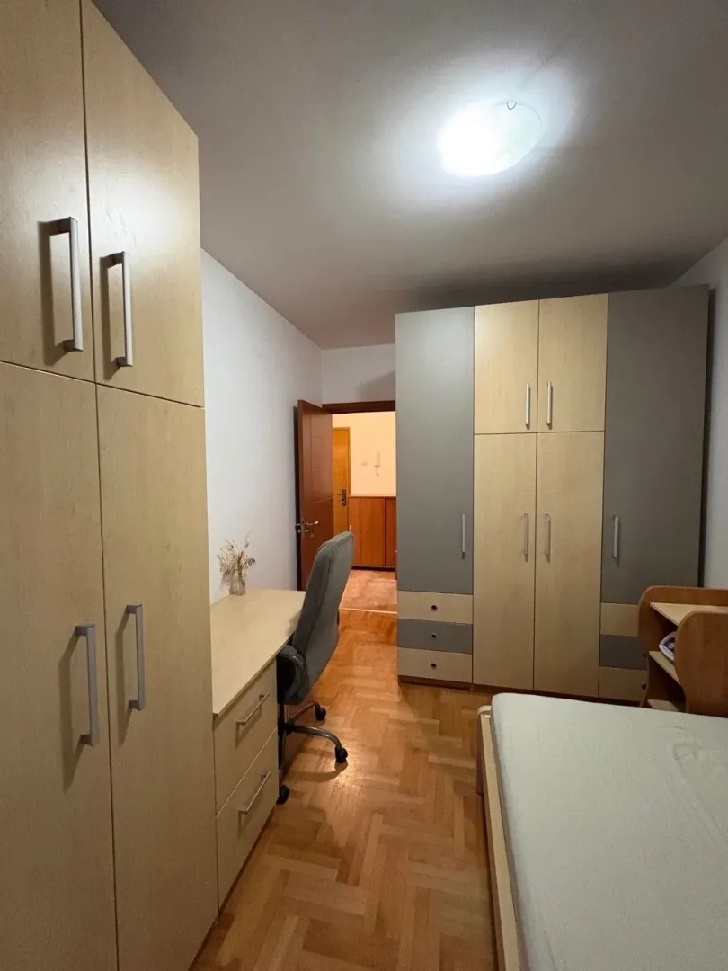 Spavaća soba sa krevetom, radnim stolom i ugradnim ormarima.
