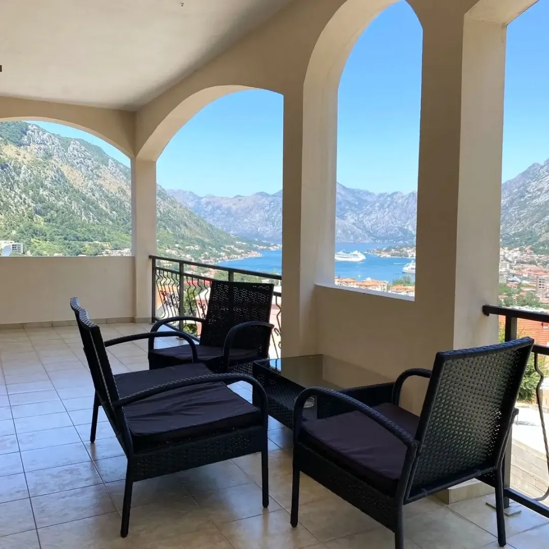 Spacious covered terrace with patio furniture and a view of the bay and mountains.