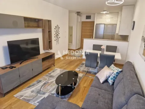 Living room with a sofa, TV, dining area, and kitchen in the background. - image 5