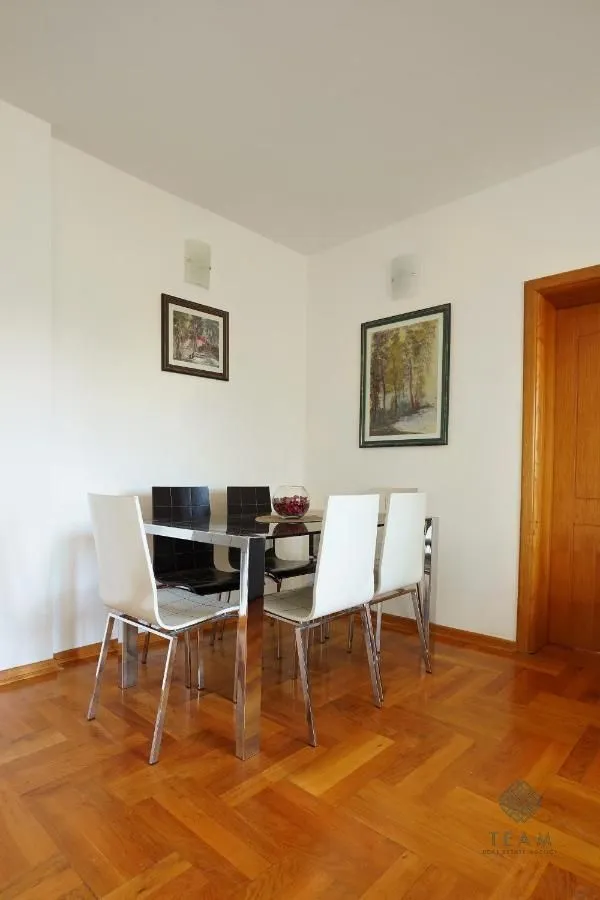 Dining area with a table, chairs, and parquet flooring.