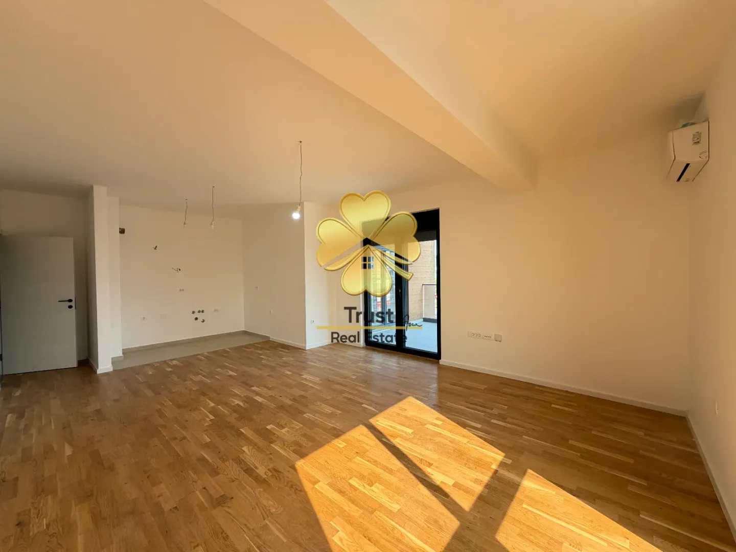 Empty living room with wooden flooring and access to the terrace.