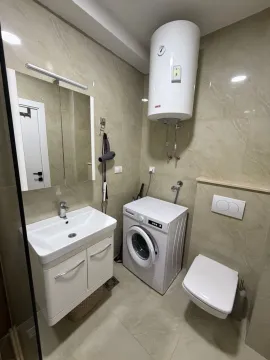 Compact bathroom with a sink, toilet, washing machine, and water heater. - image 8