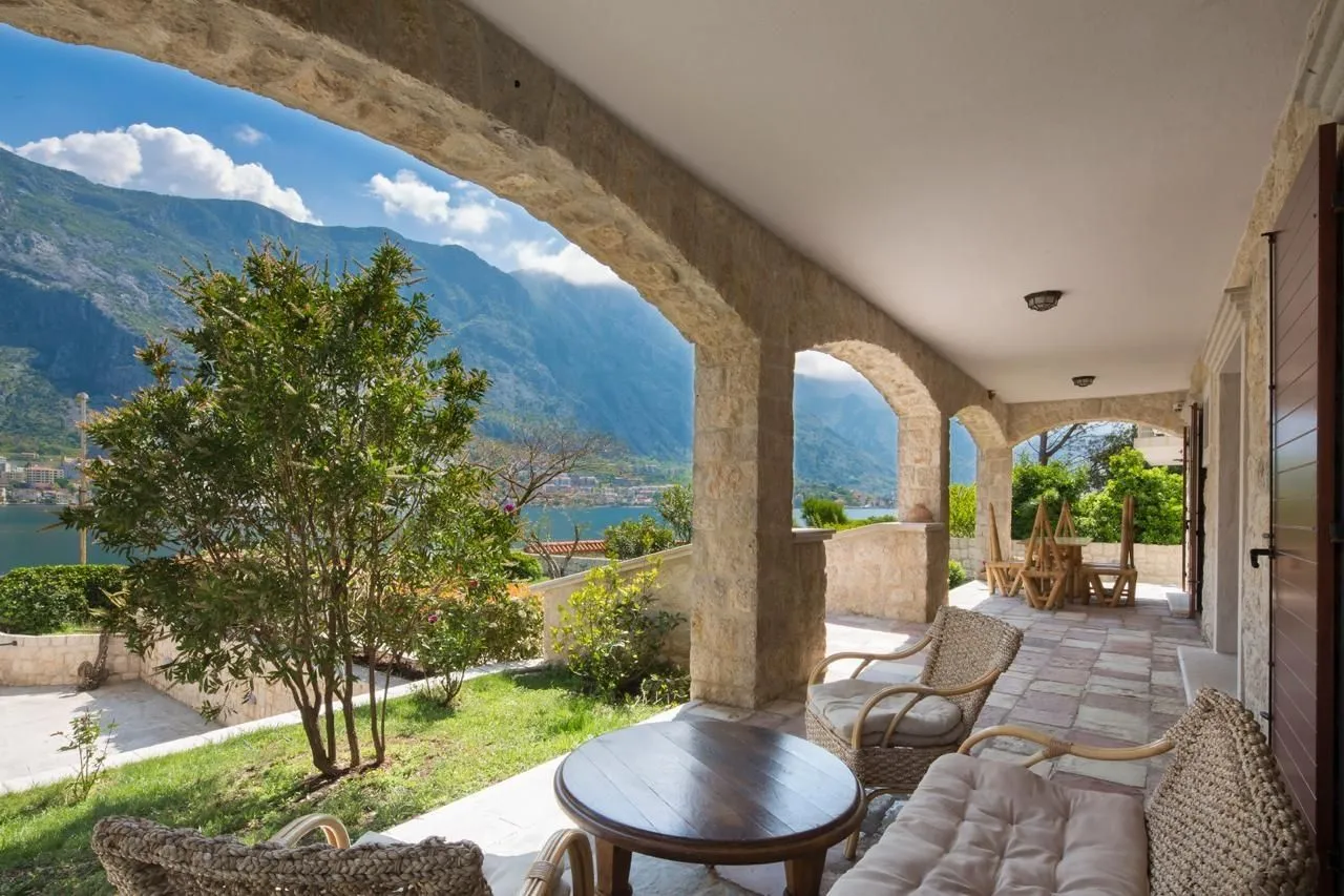 Spacious stone terrace with outdoor furniture and open views of the sea and mountains.