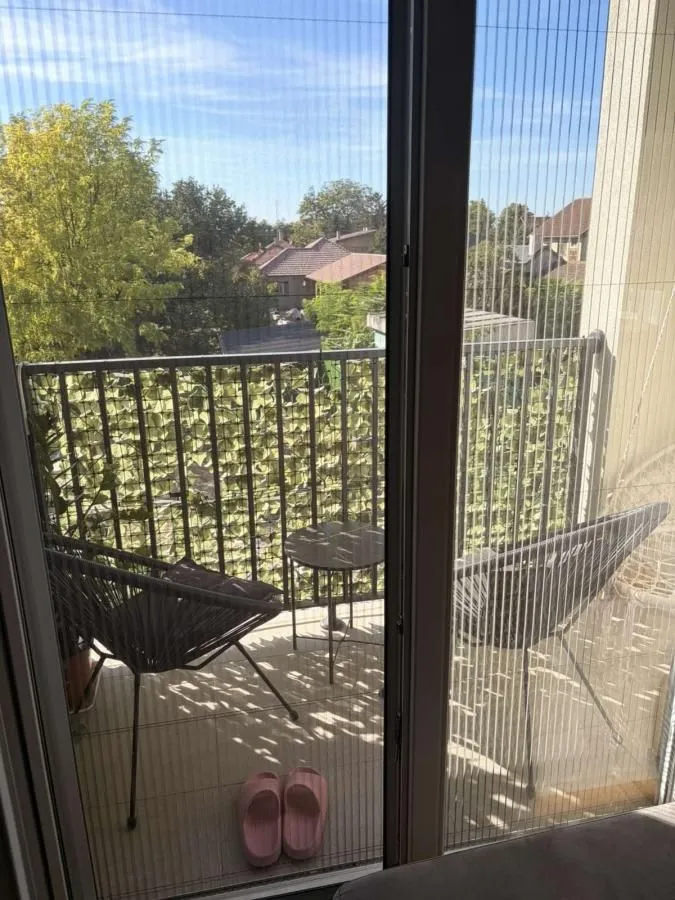 Manji namešteni balkon sa stolicama, stočićem i pogledom na naselje.