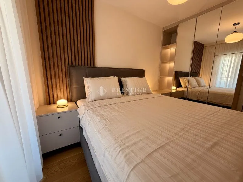 Modern bedroom with a double bed, bedside tables, and a large mirrored wardrobe.