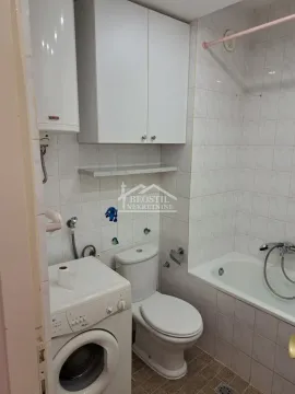 Smaller bathroom with a bathtub, toilet, water heater and washing machine. - image 7