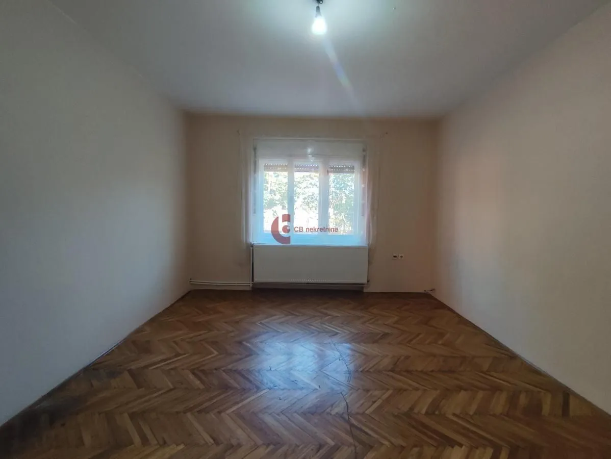 Prazna soba sa parketom i jednim prozorom.