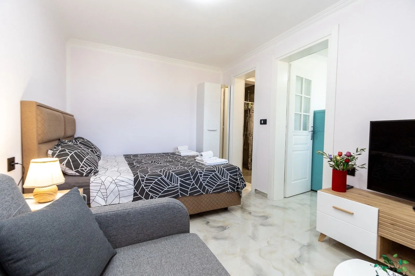 Furnished bedroom with a bed, armchair, and television.