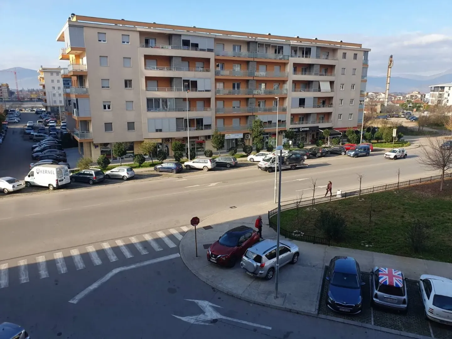 Pogled na višespratnu stambenu zgradu i ulicu ispred nje.