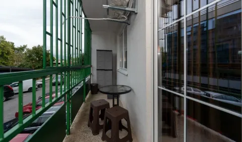 Small balcony with a green railing and patio furniture. - image 10