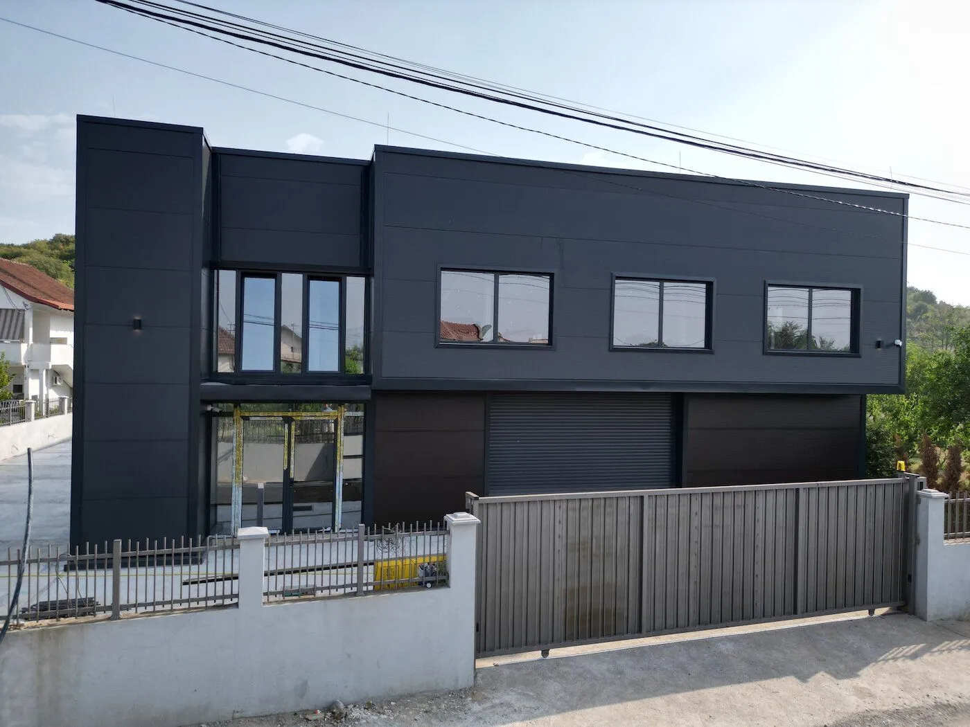 Exterior view of a modern dark-façade commercial or residential building with a fence.