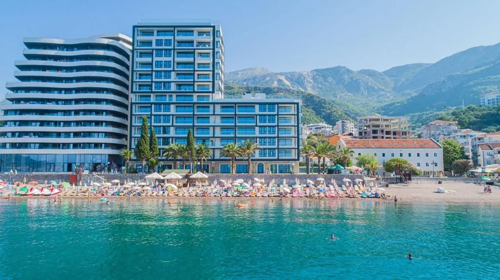 Pogled sa mora na modernu zgradu i plažu ispred.