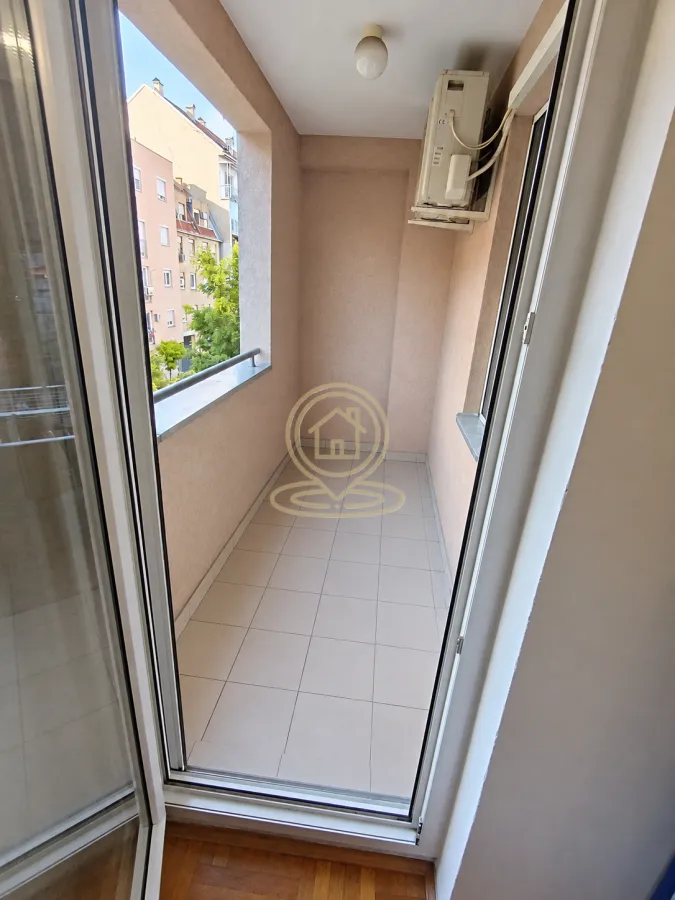 Manji zatvoreni balkon sa popločanim podom i pogledom na grad.