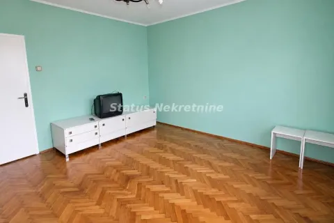 Prazna soba sa zelenim zidovima, parketom i televizorom na komodi. - image 8