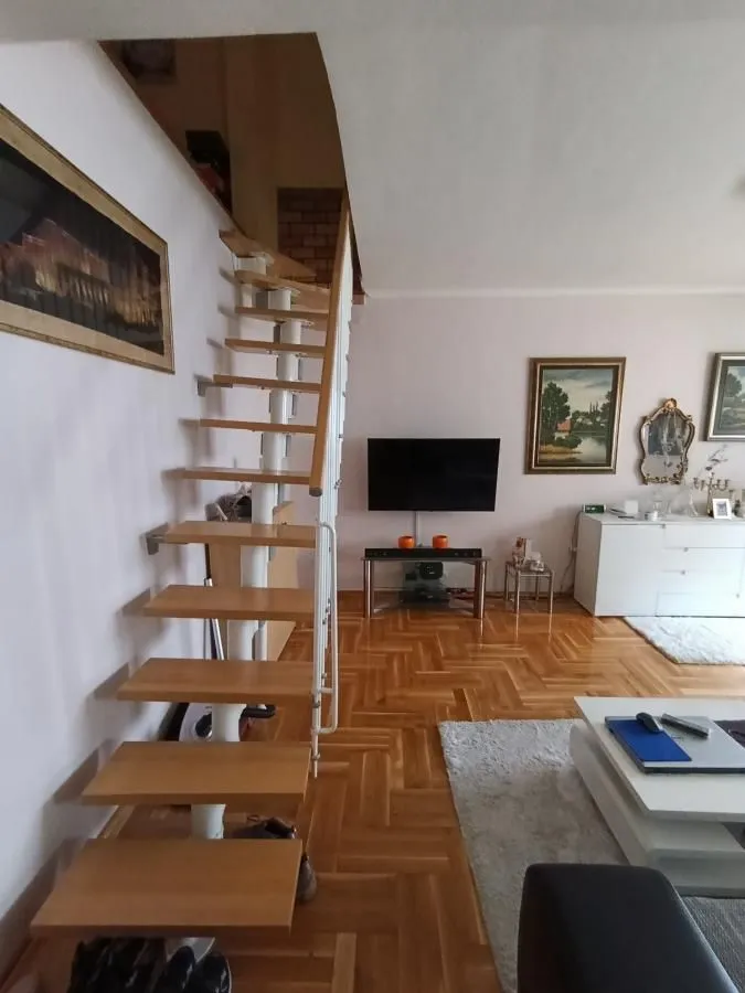 Dnevna soba sa drvenim stepeništem i parketom na podu.