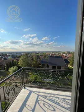 Balkon sa ukrasnom metalnom ogradom i pogledom na okolno naselje. - image 11