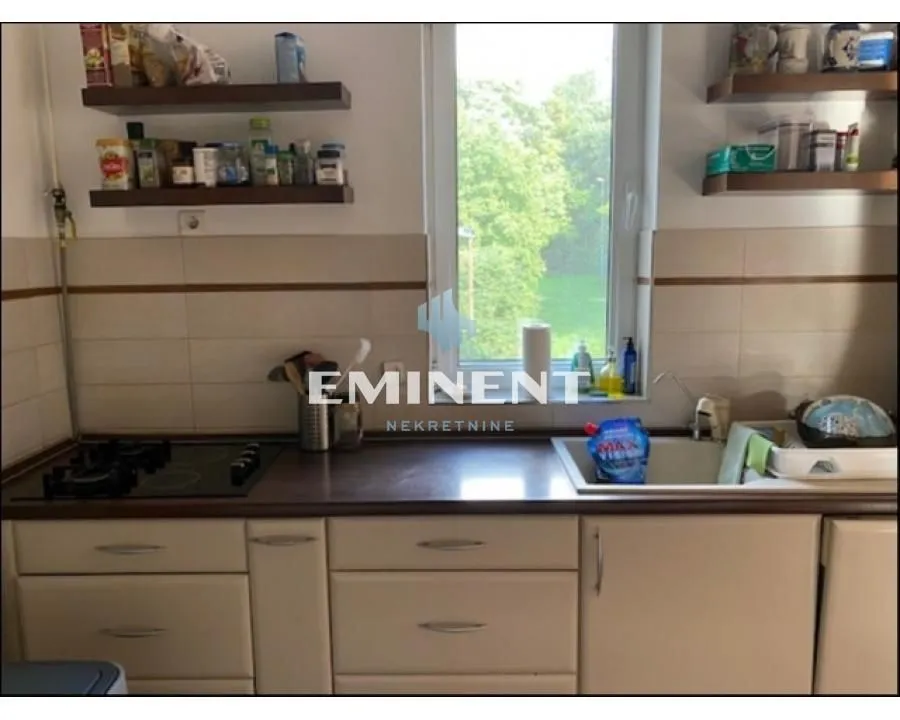 View of a part of the kitchen with a countertop, sink, and shelves.