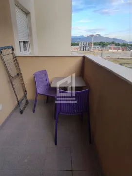 Small furnished balcony with a table, chairs, and a drying rack. - image 4