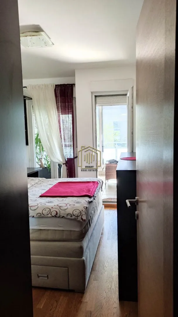 Pogled iz hodnika na spavaću sobu sa krevetom i izlazom na terasu.