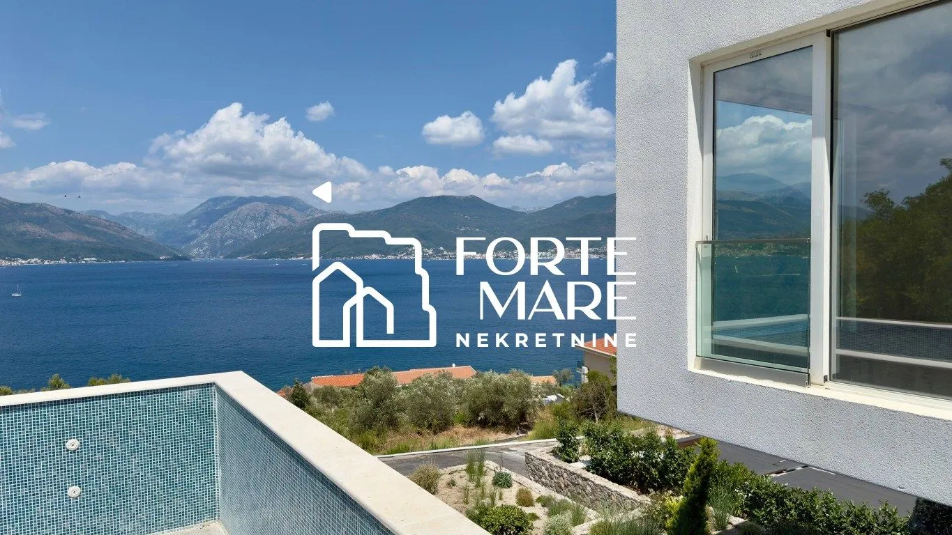 View from the terrace towards the swimming pool and the sea with a mountain landscape.