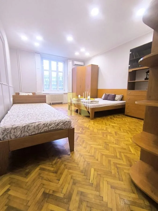 Spavaća soba sa nekoliko kreveta i drvenim ormarima.