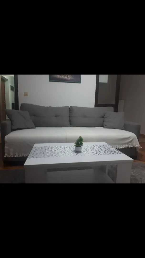Dnevna soba sa sivom garniturom i bijelim stočićem.