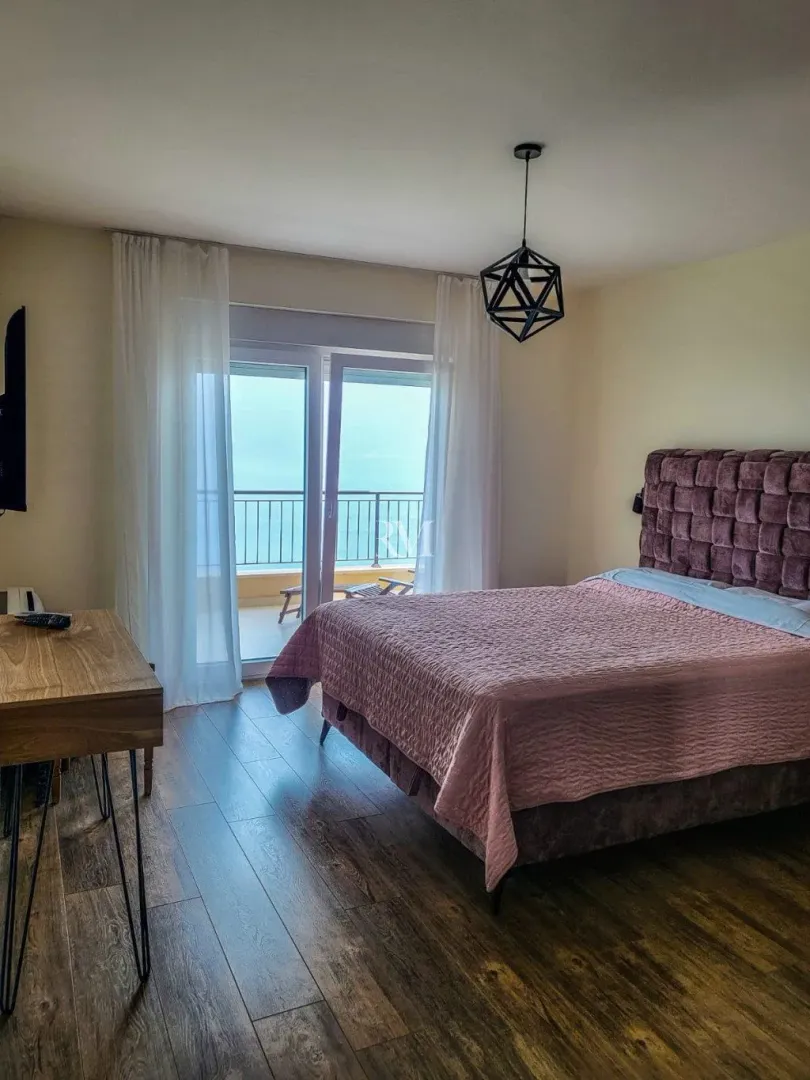 Bedroom with a double bed and access to a terrace with a sea view.