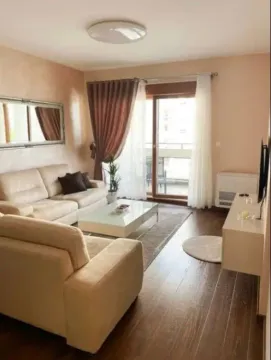 Living room with a sofa, coffee table, and balcony access. - image 2