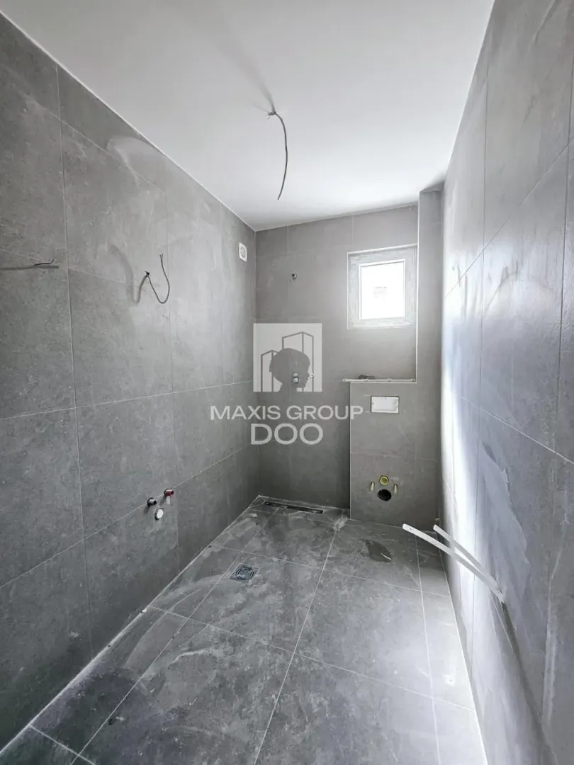 Unfurnished bathroom with grey tiles and installed plumbing.
