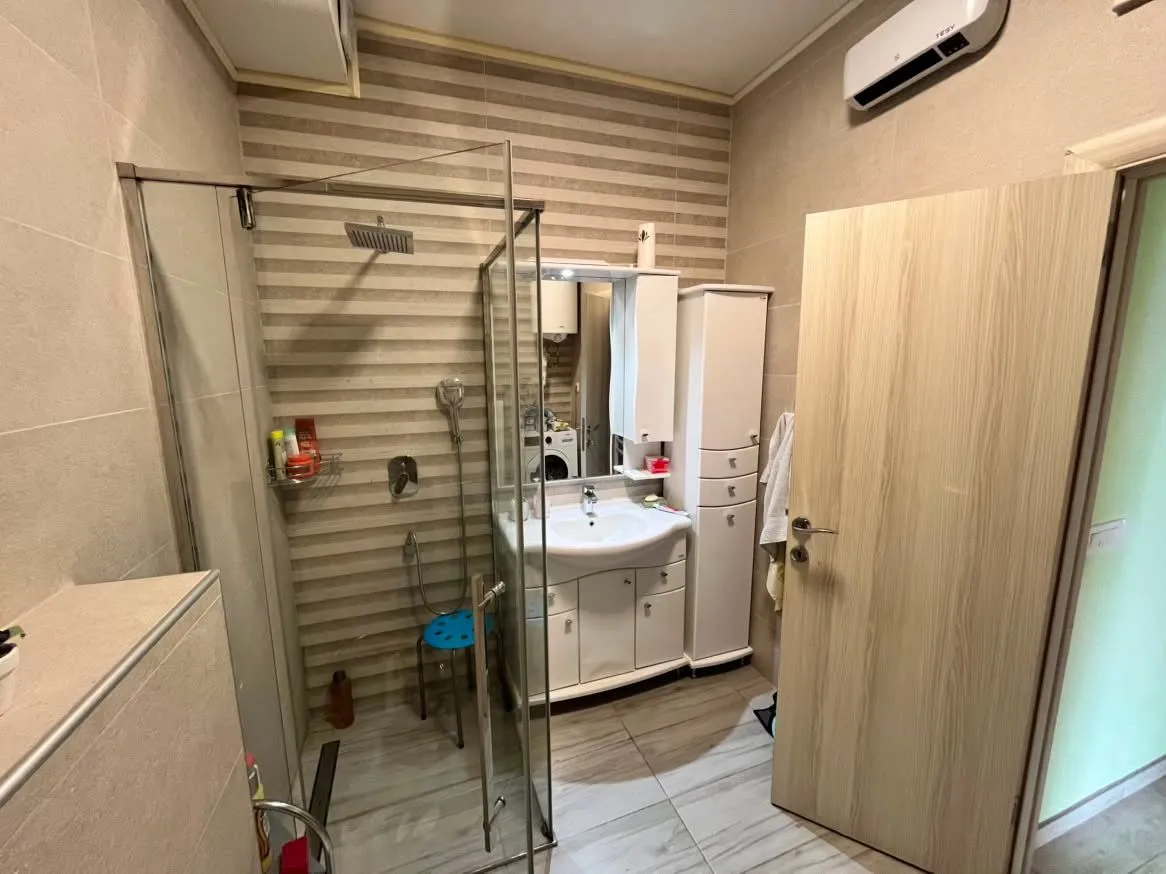 Bathroom with a shower cabin, sink, and white cabinets.
