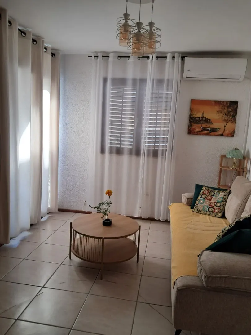 Living room with a sofa, coffee table, and windows with curtains.