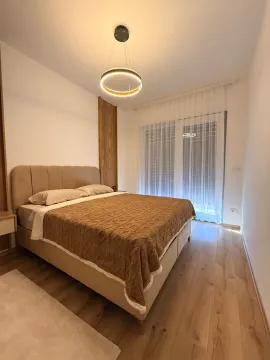 Moderna spavaća soba sa bračnim krevetom, drvenim podom i velikim prozorom. - image 4