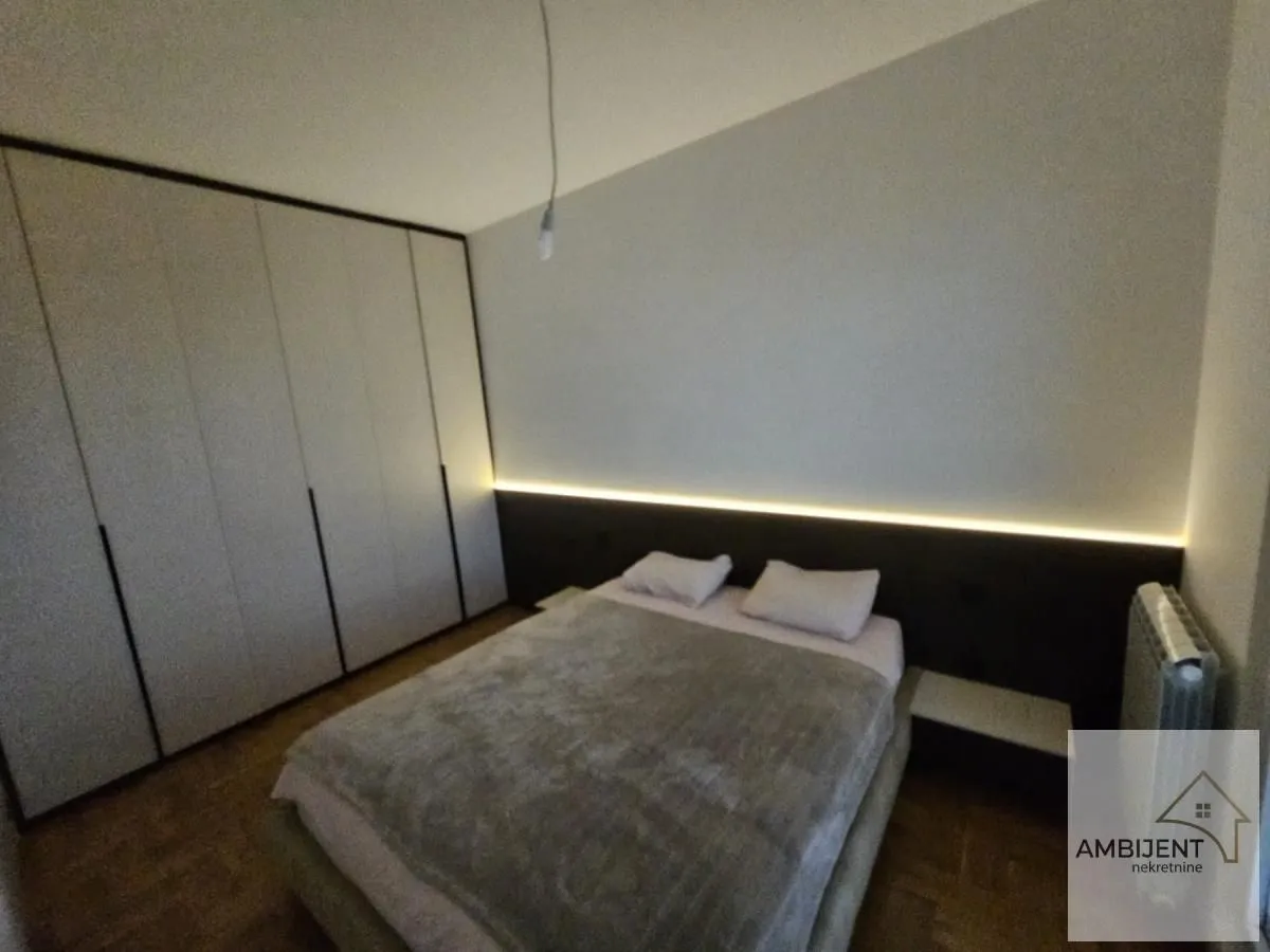 Spavaća soba sa bračnim krevetom, velikim garderoberom i ambijentalnim osvetljenjem.