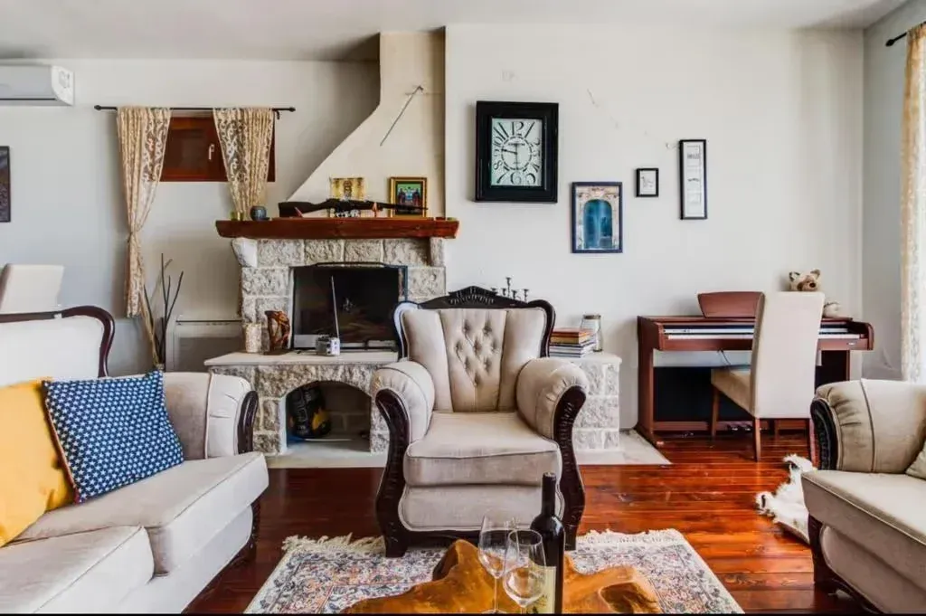 Living room with a stone fireplace, seating set and piano.