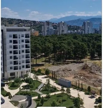 Pogled sa visine na uređeno dvorište, susjedne zgrade i planine u daljini. - image 2