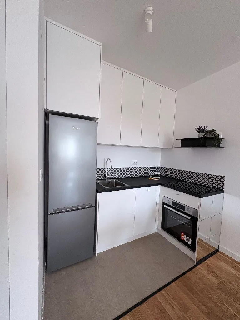 Compact white kitchen with a refrigerator and built-in oven.