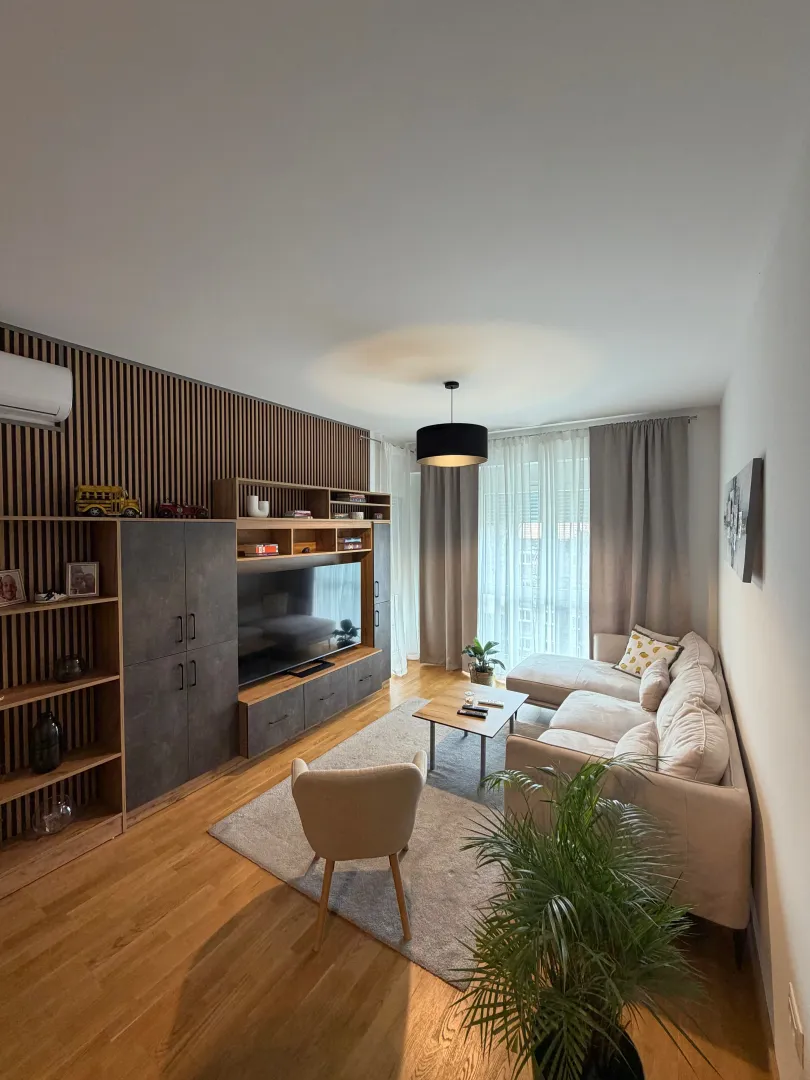 Modern and bright living room with a sofa, TV unit, and wooden wall panels.