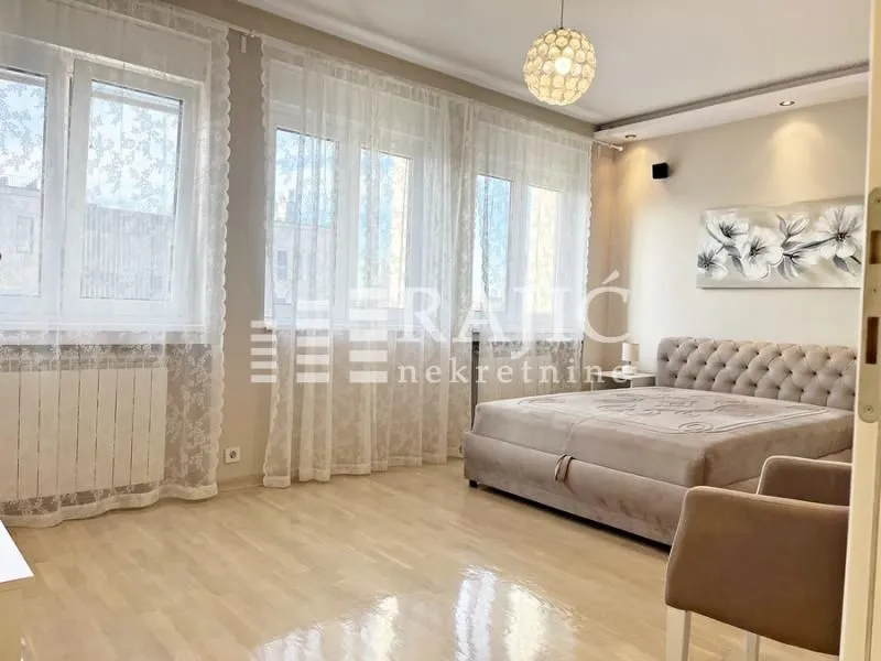 Spacious bedroom with a double bed, large windows, and hardwood flooring.