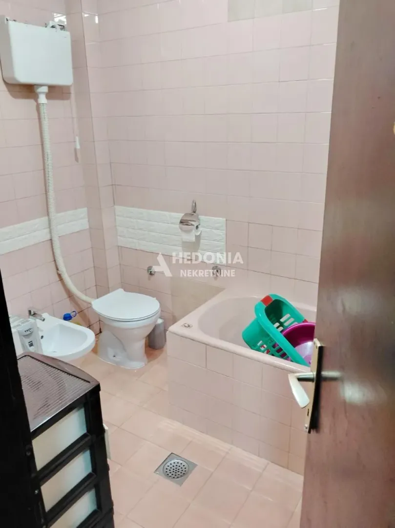 Manje kupatilo sa kadom, wc šoljom i bideom obloženo keramičkim pločicama.