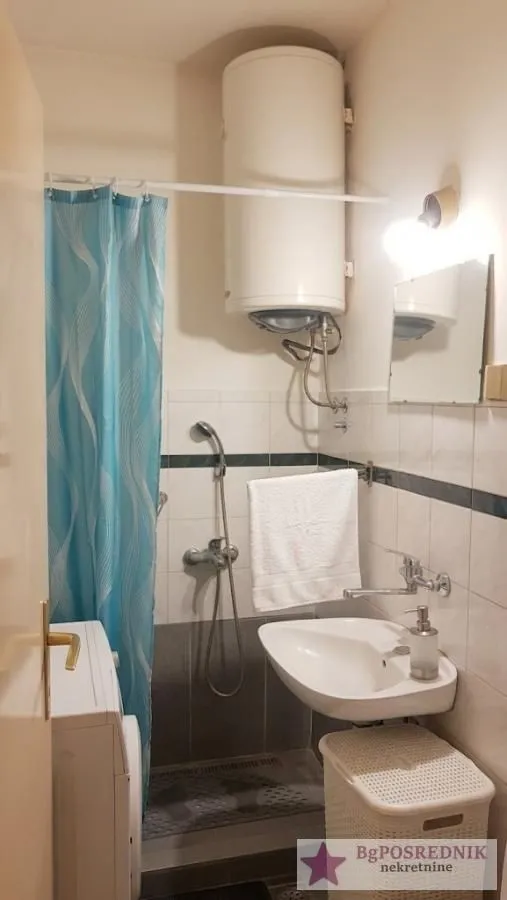 Manje kupatilo sa tuš kabinom, umivaonikom i bojlerom.