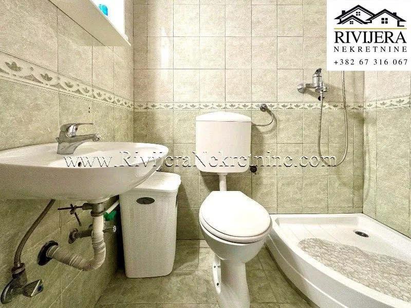 Kupatilo obloženo keramičkim pločicama sa umivaonikom, wc šoljom i tuš kabinom.