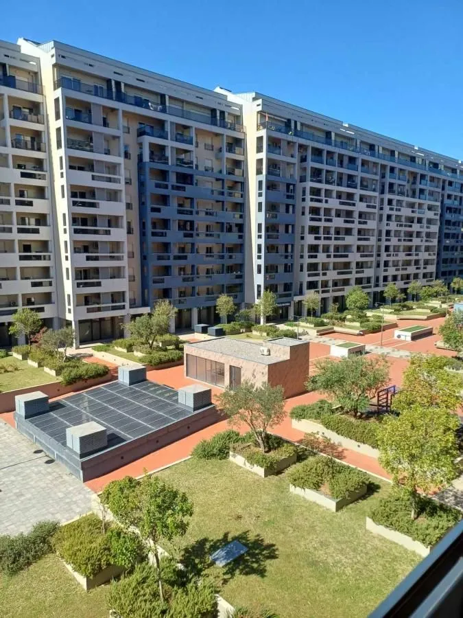 Pogled na moderno stambeno naselje sa uređenim dvorištem i zelenilom.