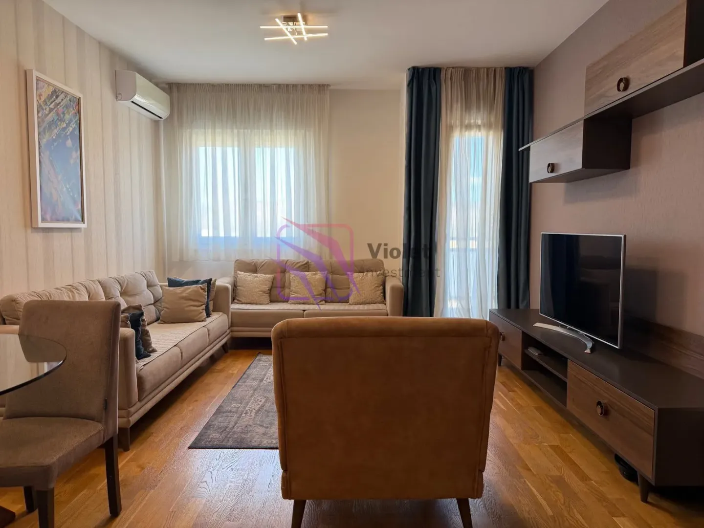 Namještena dnevna soba sa garniturom, foteljom i televizorom.