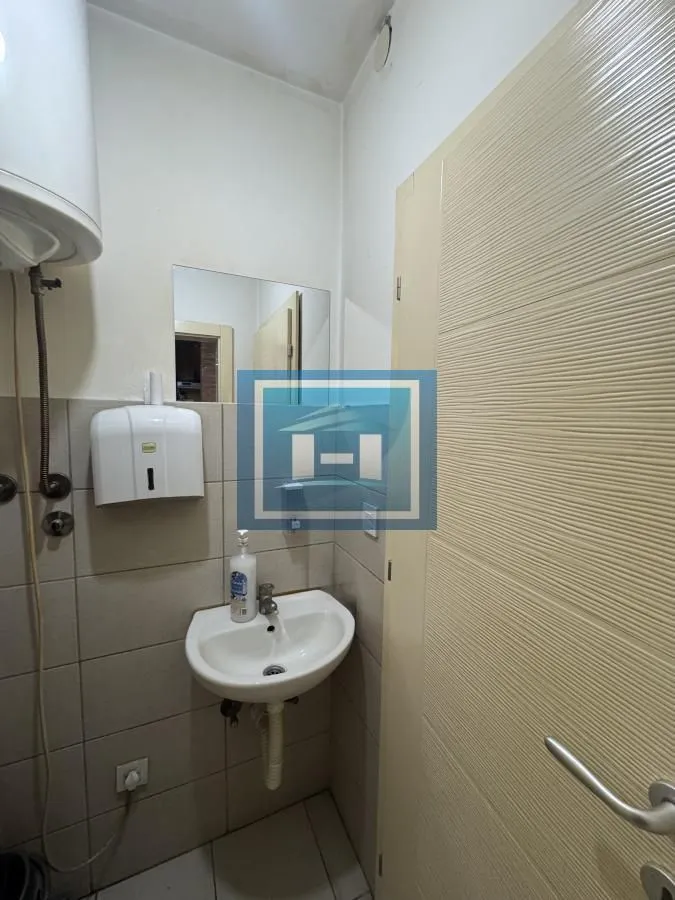 Small bathroom with a sink, water heater, and tiling.