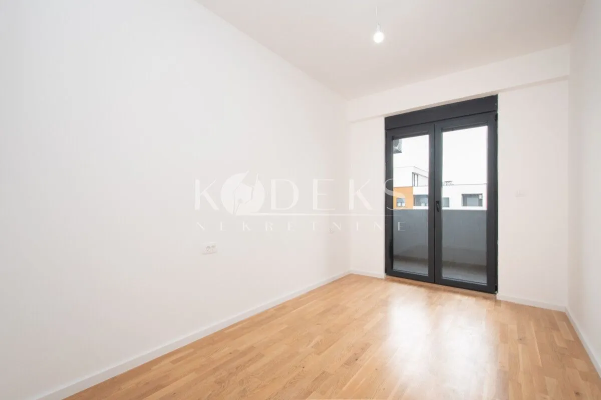 Empty bright room with parquet flooring and access to the terrace.