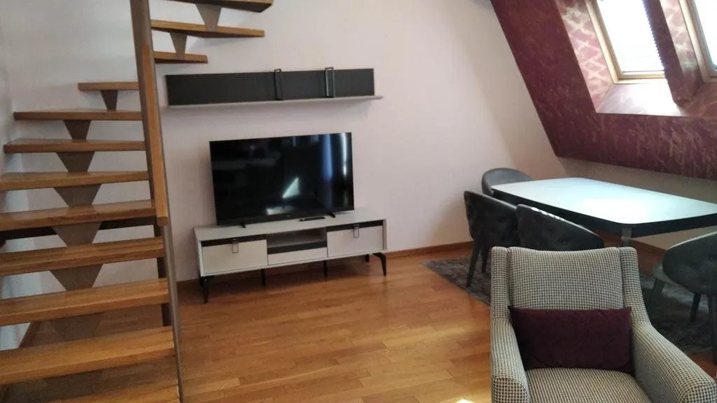 Dnevni boravak sa drvenim stepeništem i trpezarijskim dijelom u potkrovlju.